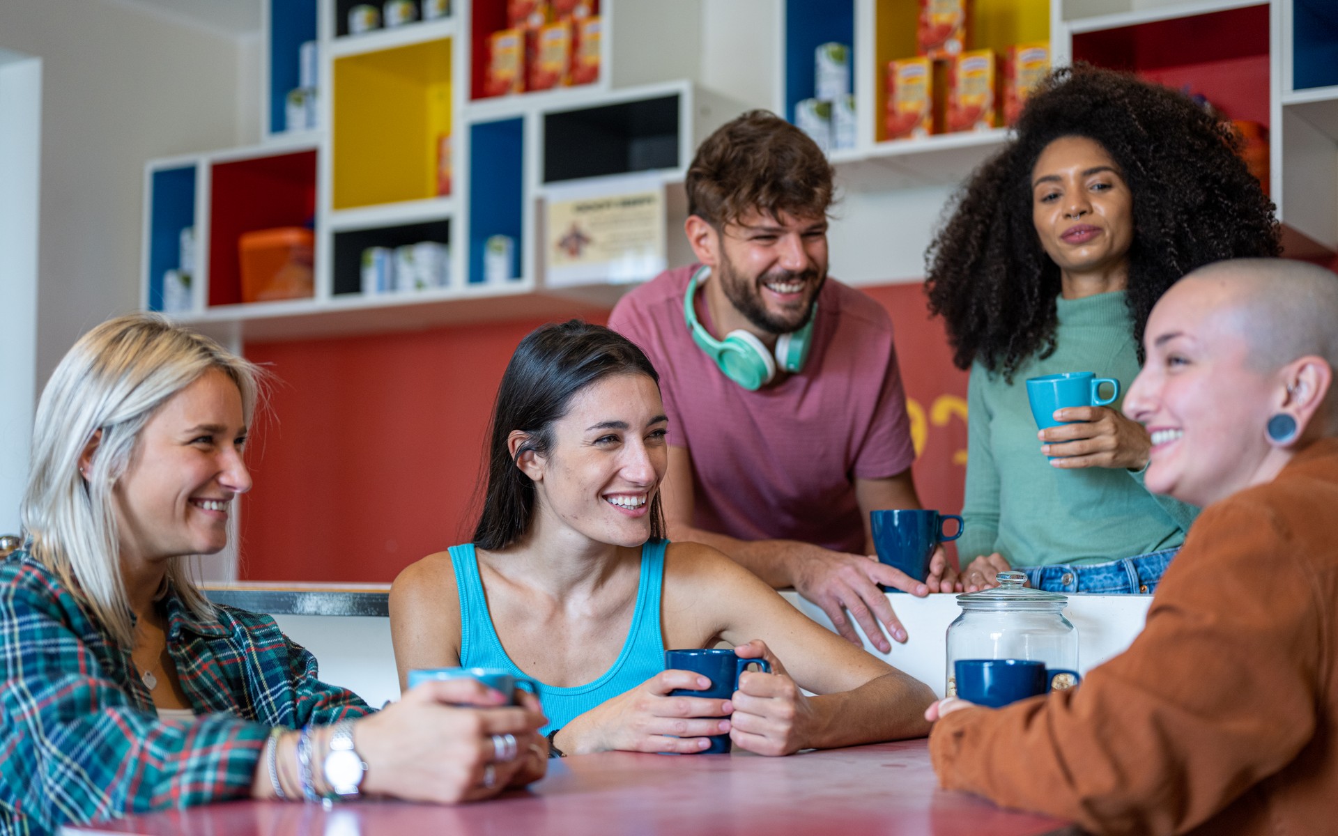 young people from generation z having braekfast in living room of hostel, concept of traveling and cheap holidays around the world, diverse young women and one only man