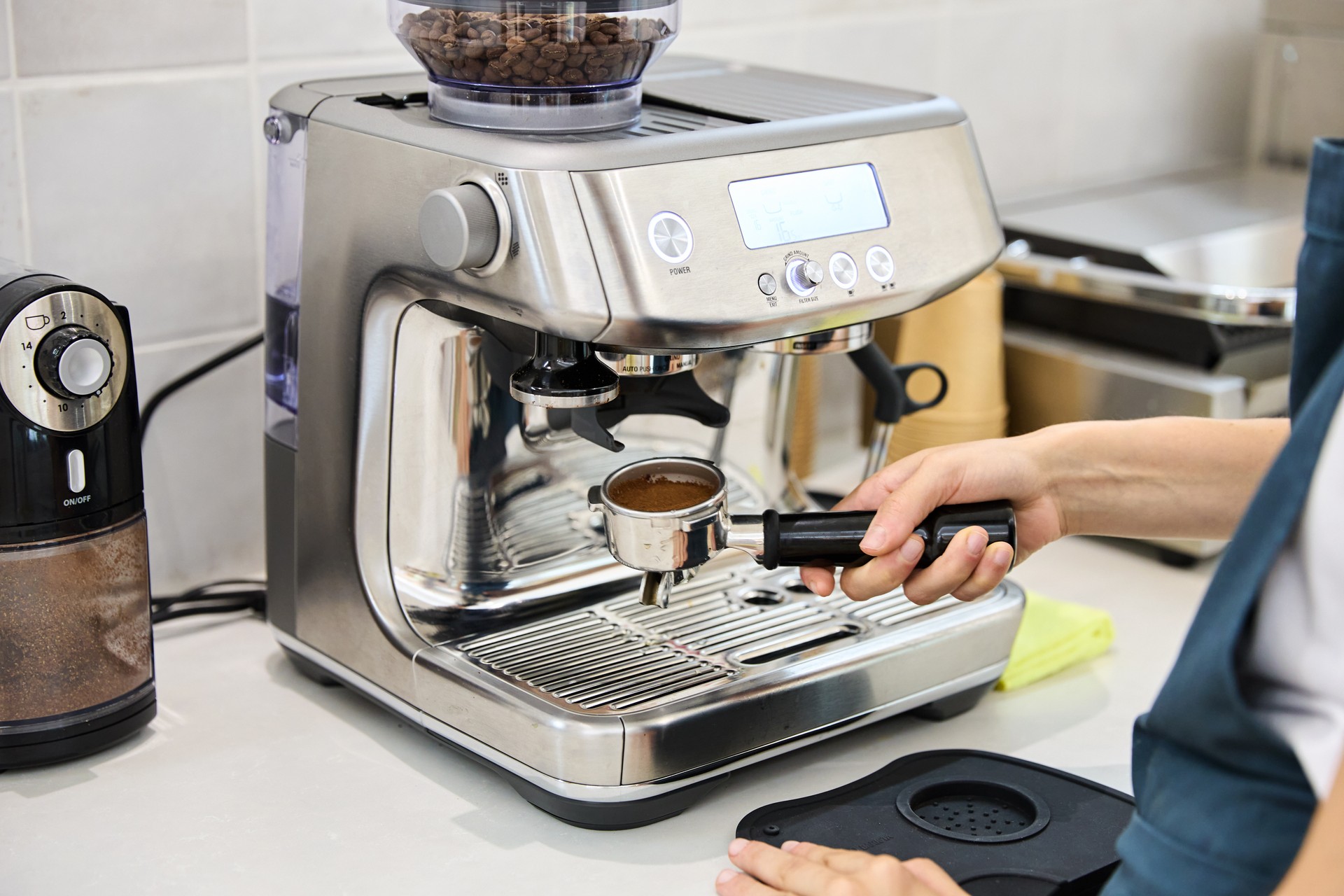 Close-up of the hands of an unrecognisable barista preparing a cup of coffee in a modern electronic coffee machine.